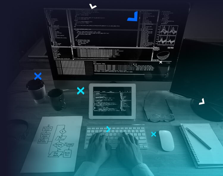 Person coding on a desk with notes, an iPad, and a computer