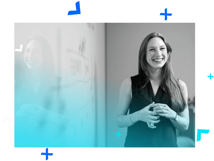 Woman smiling with a marker in her hands next to a whiteboard